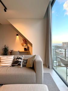 uma sala de estar com um sofá e uma grande janela em MOLO roof - stylish penthouse with marina view Blankenberge within walking distance from the sea - 15 km from Bruges em Blankenberge