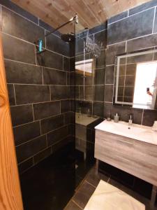 a black tiled bathroom with a sink and a mirror at Studio Sainte Marie in Lanslebourg-Mont-Cenis