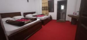 2 camas en una habitación con alfombra roja en Thalagala Oya Resort & Restaurant en Nuwara Eliya