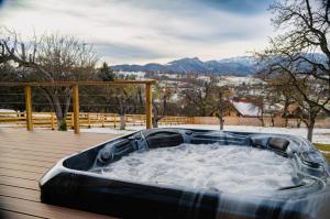 una vasca idromassaggio seduta su un ponte con neve di Zenit Chalet Sohodol-Bran a Sohodol