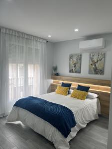 1 dormitorio con 1 cama grande con almohadas azules y amarillas en Matallana 32, en Herencia