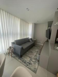 a living room with a couch and a tv at Apart moderno 3 suites 2 vagas de garagem e quadra do mar in Itapema