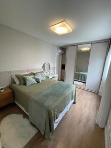a bedroom with a large bed and a mirror at Apart moderno 3 suites 2 vagas de garagem e quadra do mar in Itapema
