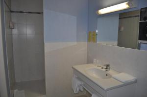 a bathroom with a sink and a shower with a mirror at Hotel Du Rocher in Le Caylar