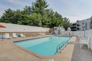 a swimming pool with white chairs and a building at LAKEFRONT PENTHOUSE FULLY UPGRADED PANORAMIC VIEWS BOAT SLIP INDOOR OUTDOOR POOL in Wisconsin Dells