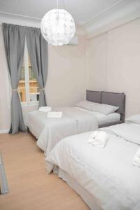 Dieses weiße Zimmer verfügt über 3 Betten und einen Kronleuchter. in der Unterkunft Lemon House in the center Pesante in Sanremo