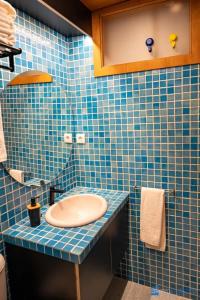 La salle de bains est pourvue de carrelage bleu, de toilettes et d'un lavabo. dans l'établissement Y Trendy Arthouse Boavista, à Porto