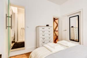 una camera da letto bianca con cassettiera e specchio di Historical Gem in Baixa a Lisbona