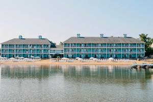 ein großes blaues Gebäude mit weißen Stühlen am Strand in der Unterkunft Sugar Beach Resort Hotel in Traverse City