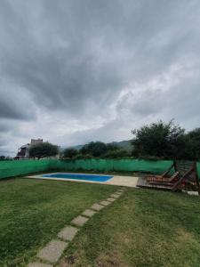 a swimming pool in a yard with a green fence at Casa om in San Roque