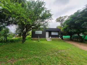 una pequeña casa negra en un patio con un árbol en Casa om en San Roque