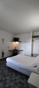 Hotel Du Rocher في لو كايلار: غرفة نوم بسرير ابيض كبير وتلفزيون