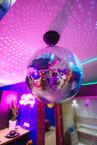 uma bola de discoteca está pendurada num tecto roxo em Capsule Boogie-Woogie - JACUZZI - SAUNA - BILLARD - JEUX - ECRAN GÉANT - FILET SUSPENDU - NETFLIX em La Louvière