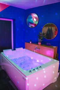 a pink tub in a blue room with a mirror at Capsule Boogie-Woogie - JACUZZI - SAUNA - BILLARD - JEUX - ECRAN GÉANT - FILET SUSPENDU - NETFLIX in La Louvière