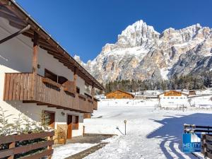 a building with a snow covered mountain in the background at Dolomites Stunning View & Garden in San Vito di Cadore