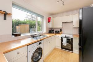 a kitchen with white cabinets and a washer and dryer at Two Bed House With Free Parking, near Train St. in Bath