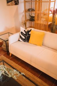 ein Wohnzimmer mit einem weißen Sofa und einem gelben Kissen in der Unterkunft Beautiful Olive's cave house in Lomo de Arico