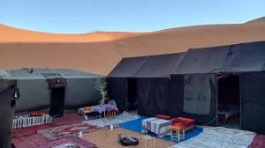 ein Zelt in einer Wüste mit Tischen und Stühlen in der Unterkunft Gambe Camp in Adrouine