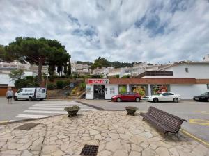 a parking lot with a bench in front of a store at Cala Salions Balandro II Tossa de mar in Cañet de Mar
