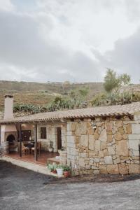 ein Steinhaus mit einer Steinmauer in der Unterkunft Beautiful Olive's cave house in Lomo de Arico