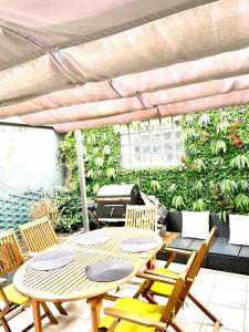 eine Terrasse mit einem Tisch, Stühlen und einem Grill in der Unterkunft Bel Appartement terrasse privée à 5 minutes du métro in Romainville