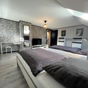 um quarto com 2 camas e uma parede de tijolos em Le Ravel Maison em Burg-Reuland