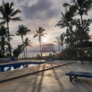 um resort com piscina, palmeiras e oceano em HOTEL PRAIA DA PAIXÃO em Prado