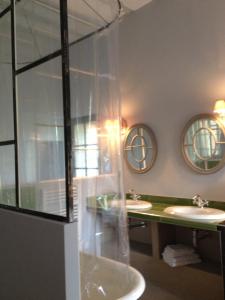 a bathroom with two sinks and a glass wall at L'Arcane Du Bellay in Montreuil-Bellay