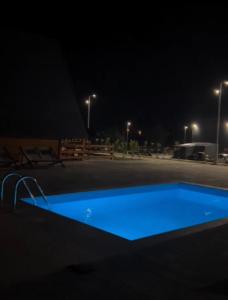 a blue swimming pool in a parking lot at night at Bungalow Damiano's in Mrkonjić Grad