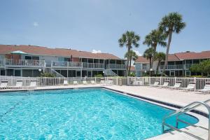 a swimming pool in front of a building with palm trees at Affordable Two Bedroom Tropical Condo - Private Beach, Pools, Hot Tub in St. Petersburg