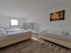two beds in a room with wooden floors at SOVA Pension Baunatal in Baunatal