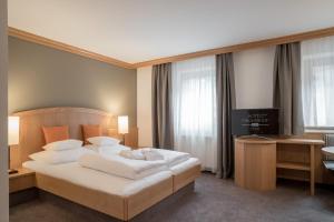 a bedroom with a bed and a desk and a television at Hotel Tyrolerhof in Sölden