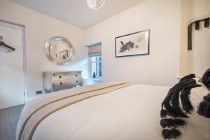 a white bedroom with a bed and a mirror at One Merewyke in Bowness-on-Windermere