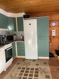 a kitchen with green cabinets and a clock on the wall at Levi Piippo 2 in Kittilä