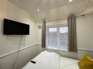 a bedroom with a flat screen tv and a bed at 3rd Studio Flat For Family Enjoyment With Private Toilet and Bathroom 134 Keedonwood Road Bromley in Bromley