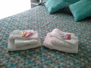 Una cama con toallas y anillos de compromiso. en M&A Apartamentos Temporales en Bahía Blanca