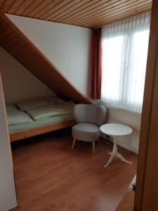 a room with a bed and a chair and a table at Pension Britta in Roetgen