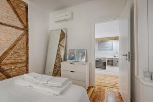 リスボンにあるArchitectural Gem in Bicaの白い家具とレンガの壁が特徴の白いベッドルーム1室