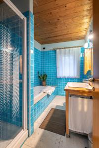 Al Cantico في Mason Vicento: حمام من البلاط الأزرق مع حوض استحمام ومغسلة