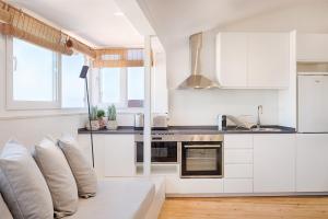 a kitchen with white cabinets and a couch with pillows at Romantic Gem in Graça in Lisbon