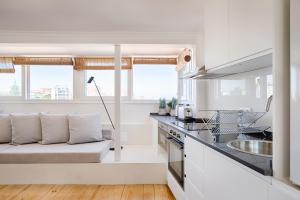a white kitchen with a couch in the middle at Romantic Gem in Graça in Lisbon +14 photos