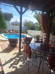 eine Terrasse mit einem Tisch, Stühlen und einem Pool in der Unterkunft Au Jardin d'Armand in Sant Pere de Ribes