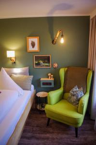 a bedroom with a bed and a green chair at Hotel Tenne in Sankt Anton am Arlberg