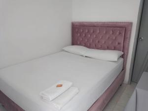 Cama blanca con cabecero rosa y almohadas blancas en Hotel Mileniun Valledupar en Valledupar
