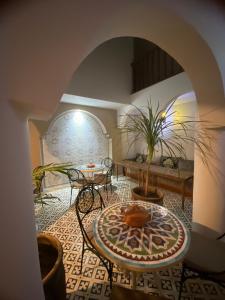 un soggiorno con tavolo e sedie in camera di Riad D’AR GANne by Carole a Essaouira