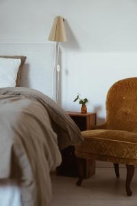 a bedroom with a bed and a chair and a lamp at Axatorpsgården in Trelleborg