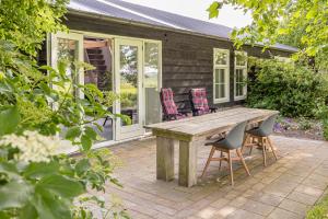 a patio with a wooden table and chairs at Het Kamphuis, landelijk slapen in Heerhugowaard