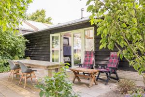 un patio con sedie, tavolo in legno, tavolo e sedie di Het Kamphuis, landelijk slapen a Heerhugowaard