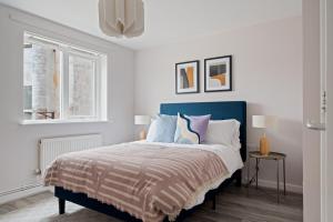 a white bedroom with a bed with a blue headboard at Stylish 2 Bed Flat in Vibrant East London in London