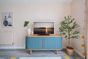 a tv on top of a blue cabinet in a living room at Stylish 2 Bed Flat in Vibrant East London in London